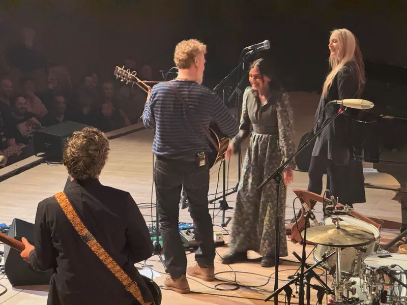 Glen playing guitar facing a young woman that was brought up from the audience to sing along.
