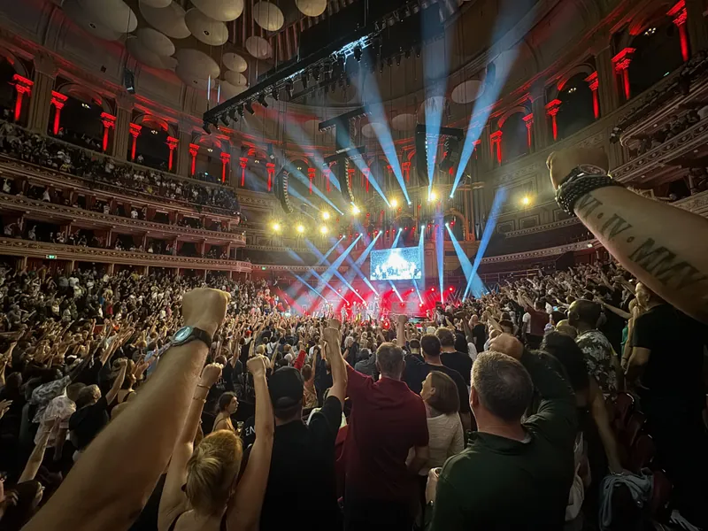 Extra wide shot of the hall. Everyone has their fist in the air looking at the stage.
