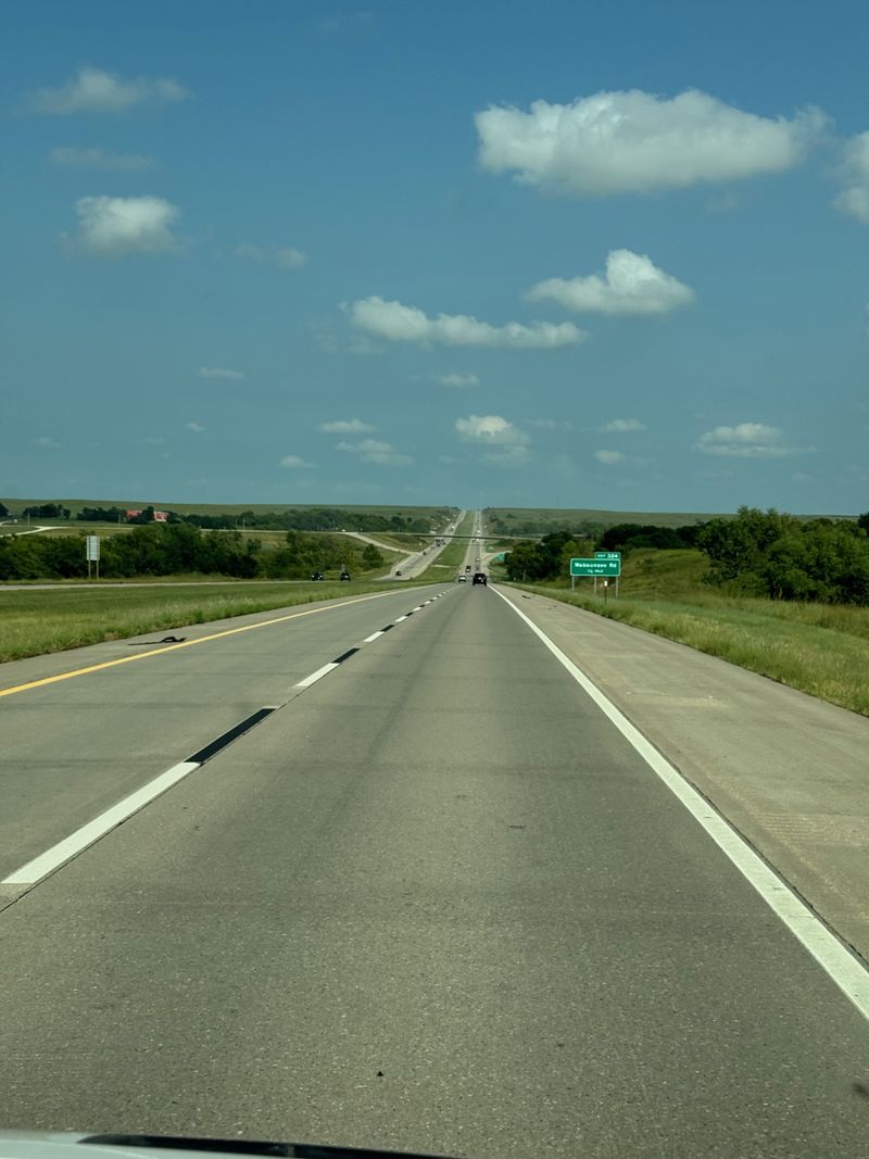 Looking straight down the road, wisping clouds over head.