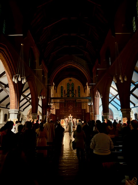 Inside a darkened church full of people with a few candles lighting the area