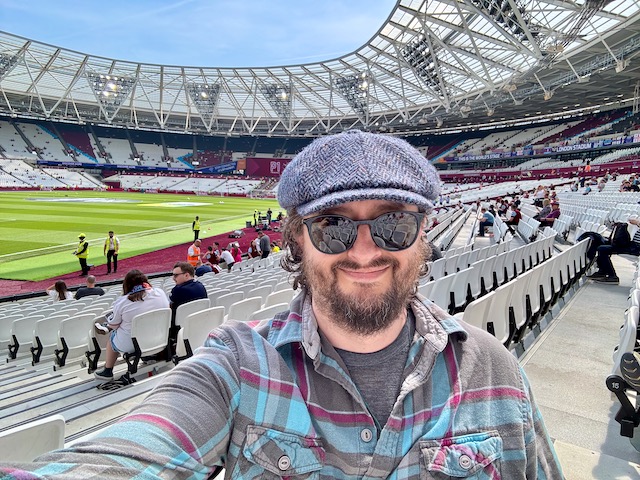 Me inside a mostly empty London Stadium with the football pitch behind me