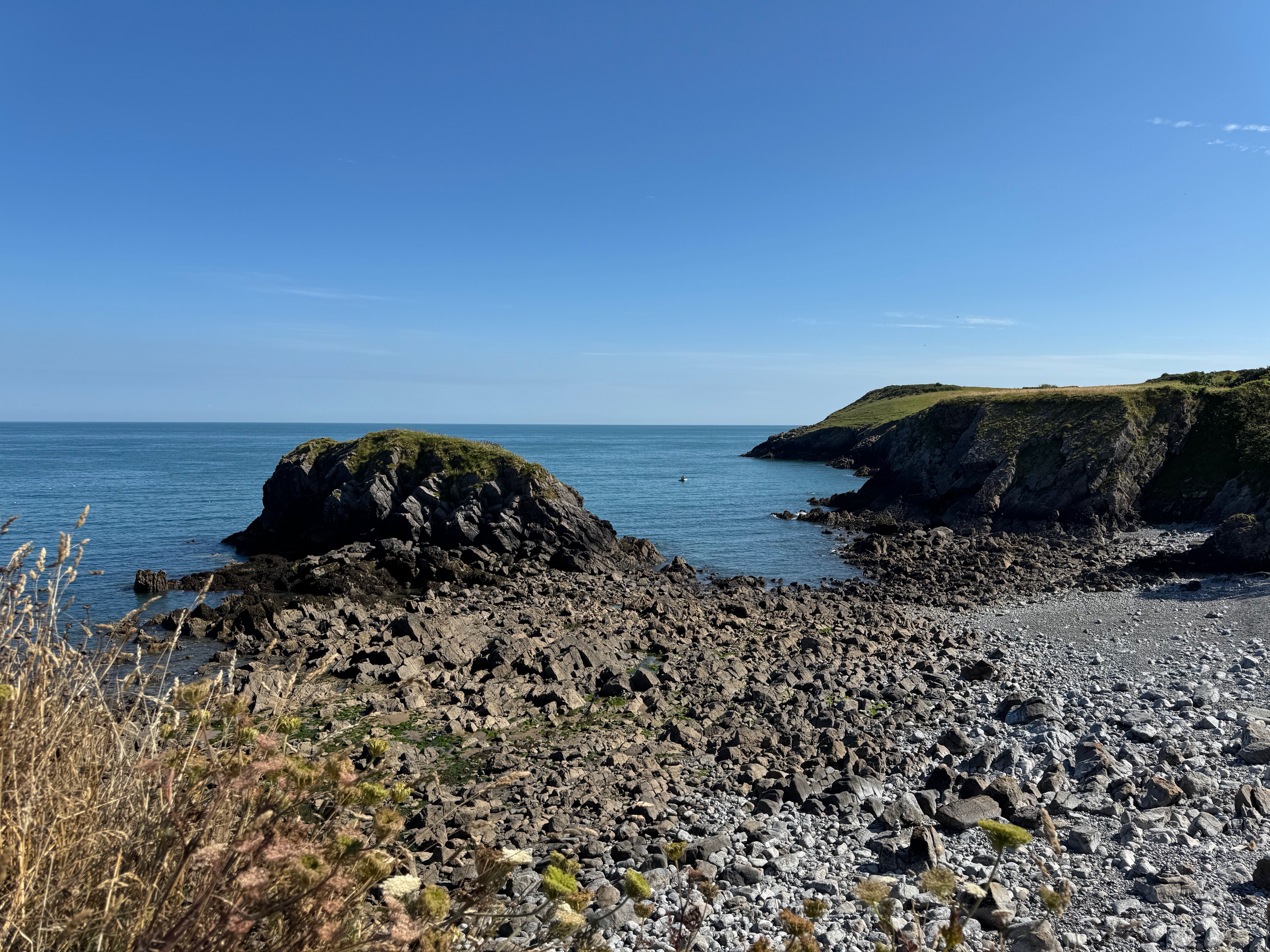 A rocky beach with a large bolder jutting out into the sea.