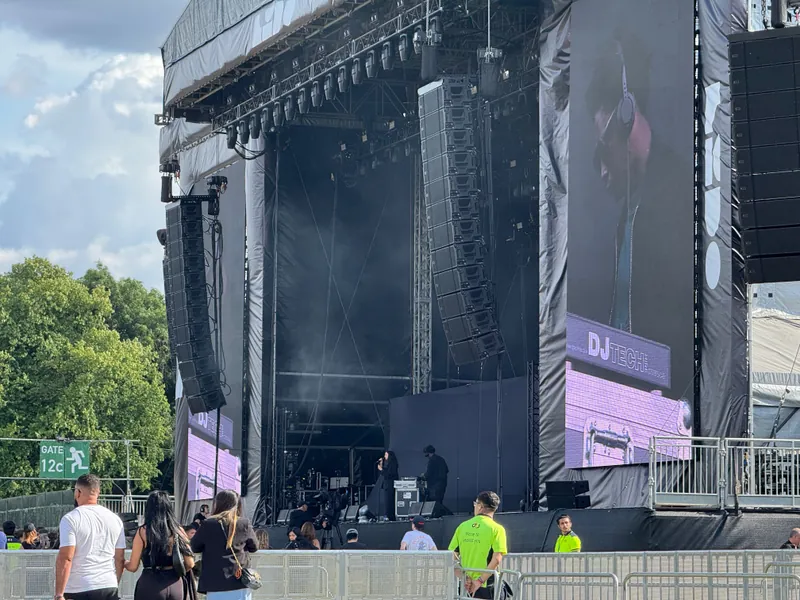 A large group of attendees surrounds a stage, all focused on the performance or presentation occurring on stage.