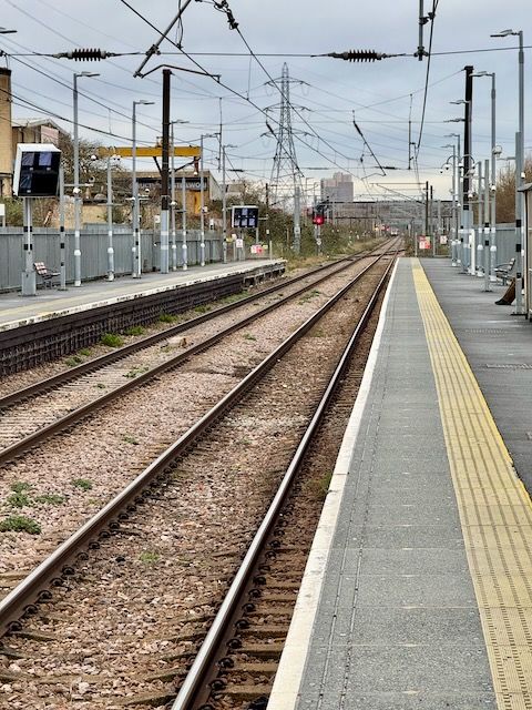 Looking down the train line from the platform. There is a single train heading off into the distance