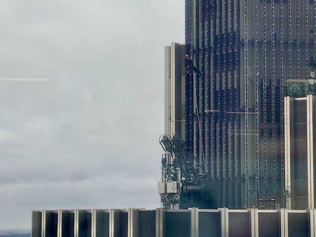 A single person repelling down the side of a skyscraper in London to fix lights on the side of the building.