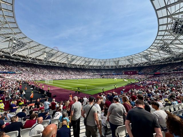 wide angle shot inside the mostly full London Stadium from the corner of the pitch a few rows back