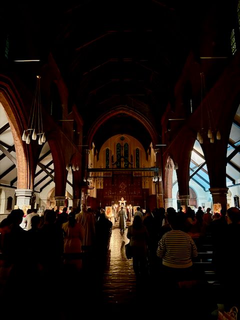 Inside a darkened church full of people with a few candles lighting the area