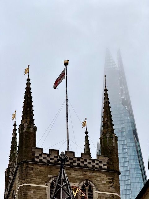 The top of Southwark Cathedral dark and grey with The Shard faintly coming through the clouds behind it